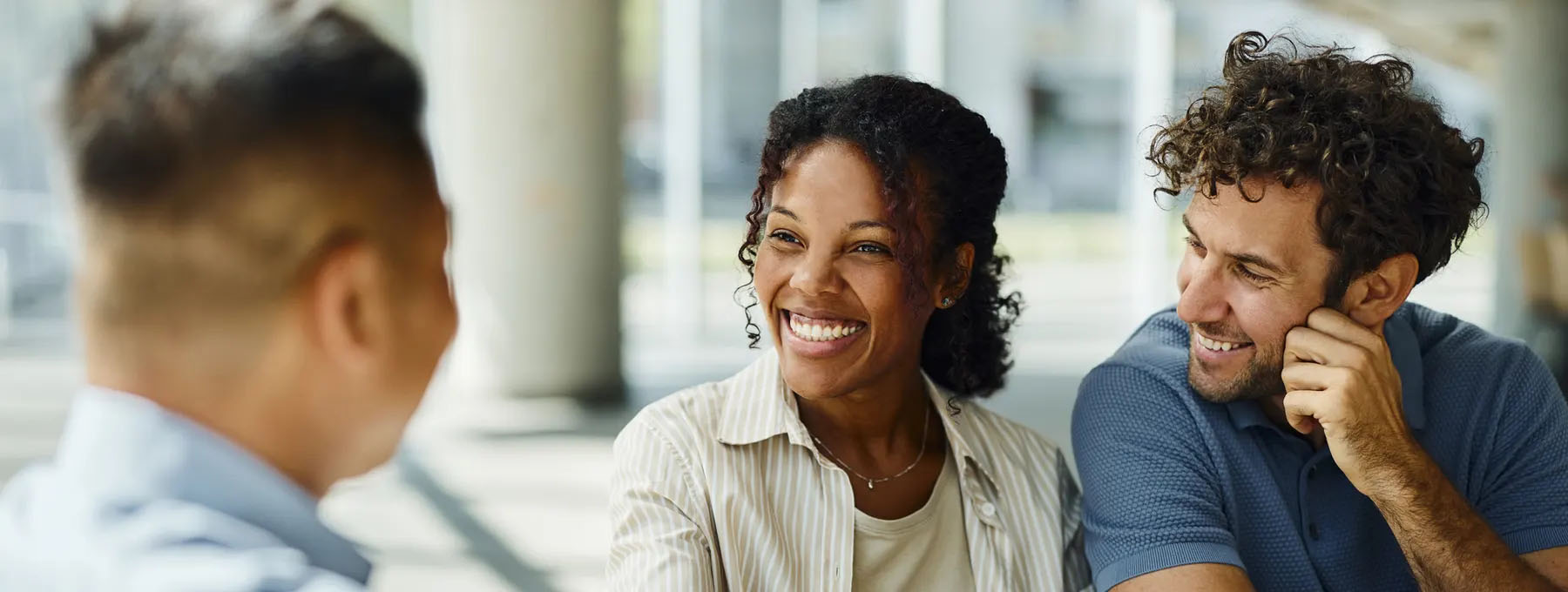 smiling bi-racial man and woman talking with man banker