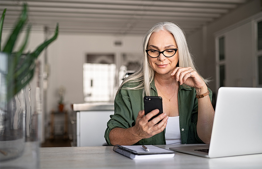 woman sitting at a desk reading a text message